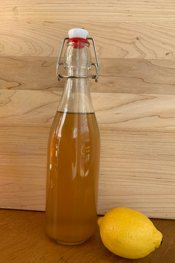 glass bottle filled with water kefir and a lemon